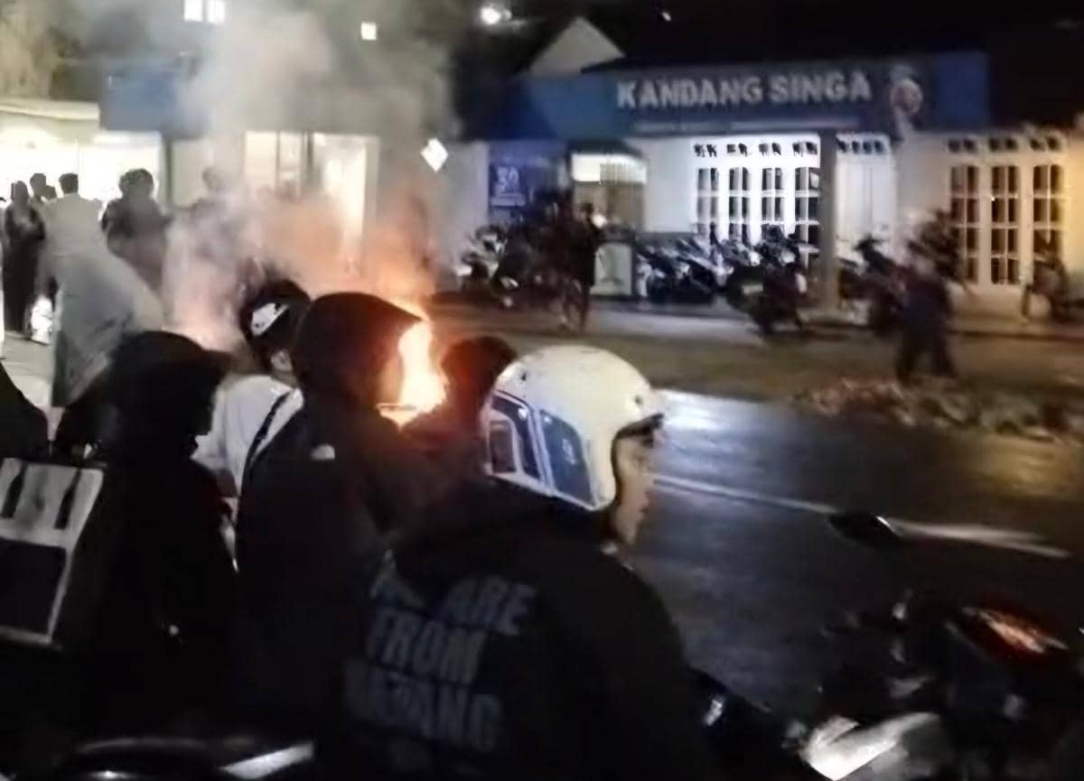 Sejumlah Aremania berkumpul di depan Kantor Arema FC pada malam hari dengan api menyala di jalan setelah kekalahan dari Persik Kediri.