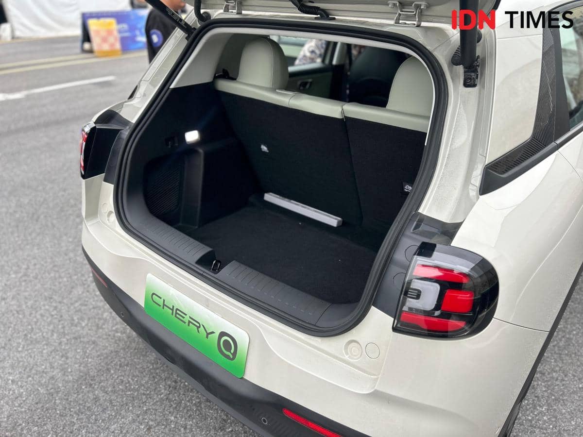 Bagasi mobil Chery Q berwarna putih terbuka menampilkan ruang penyimpanan belakang dengan kursi lipat dan lampu interior.