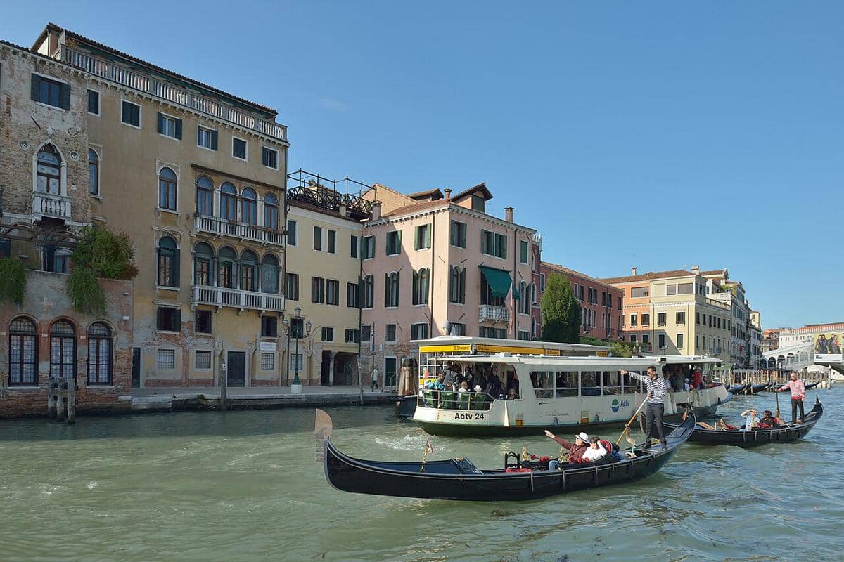 Suasana ramai di Grand Canal di Venesia, Italia. Perahu putih itu adalah vaporetto, sementara di bagian depan adalah sebuah gondola tradisional.