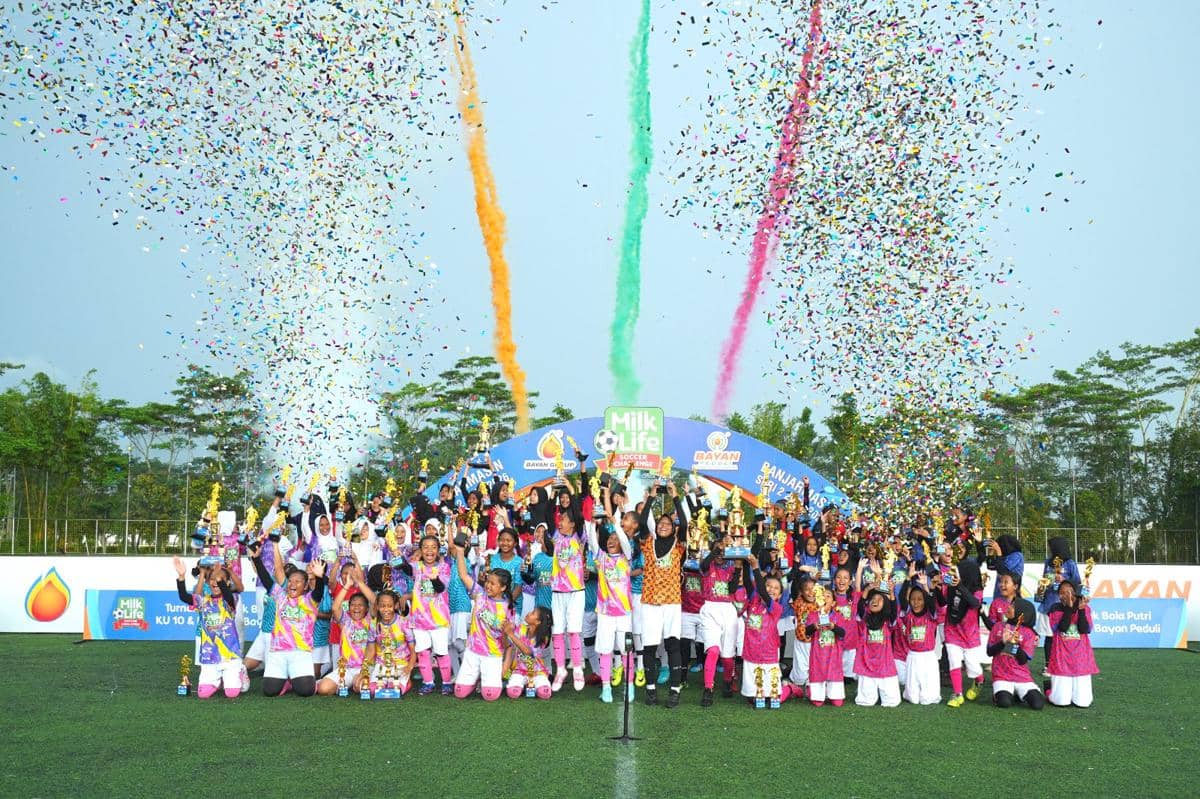 Para peserta muda merayakan keberhasilan turnamen sepak bola MLSC Banjarmasin Seri 2 2025-2026 dengan konfeti warna-warni di lapangan hijau.