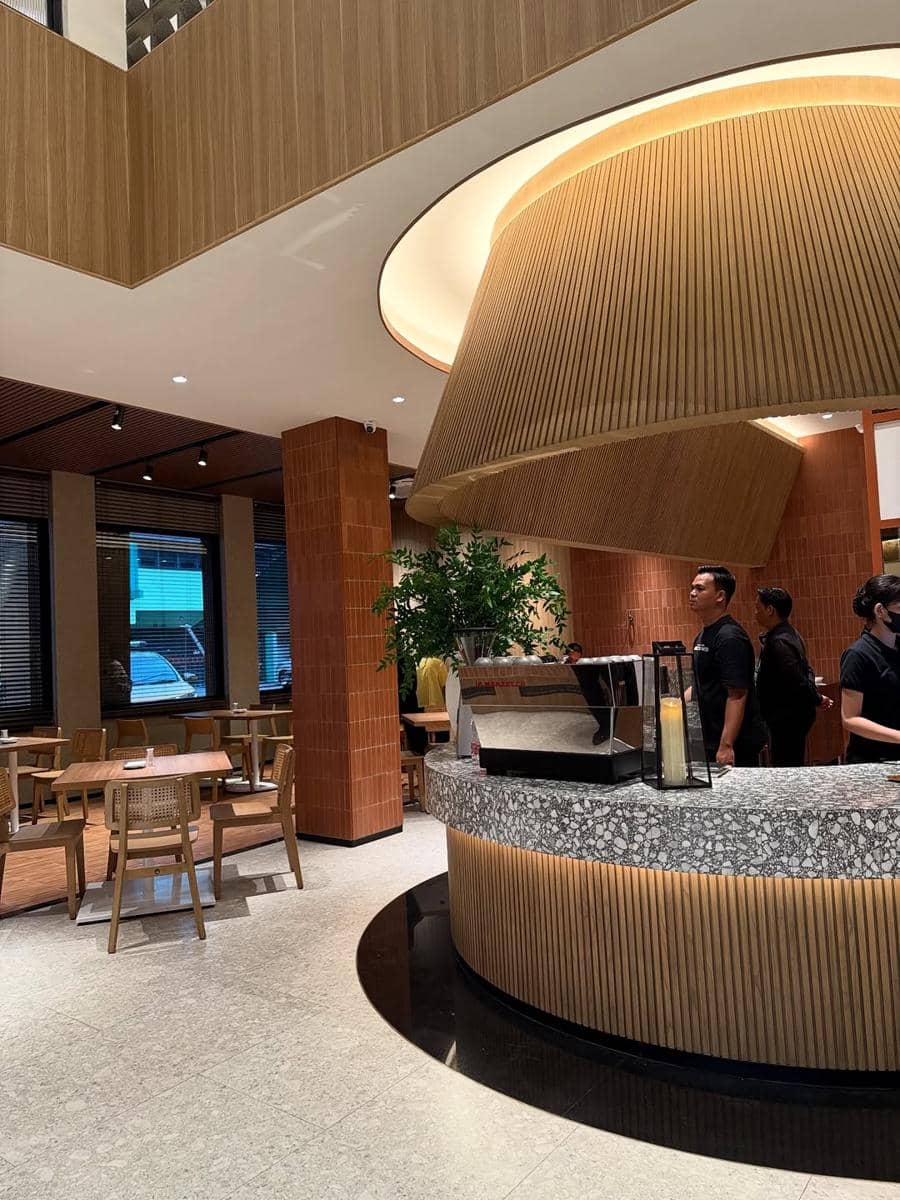 Interior modern Cafe Resto Aneka Sari Dapur Rasa di Bandar Lampung dengan desain kayu hangat, area duduk nyaman, dan barista di area kasir.