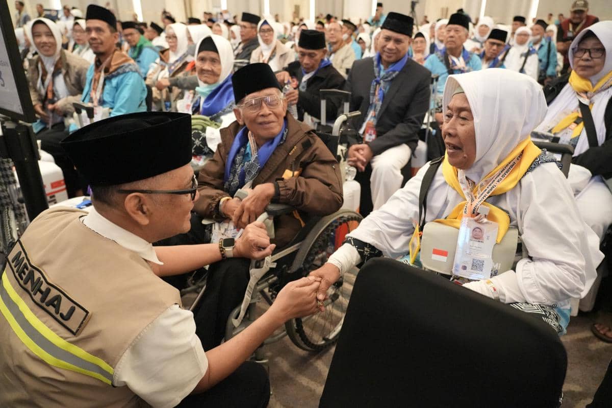 Seorang pejabat Kementerian Haji dan Umrah berbincang dan memberi semangat kepada jemaah haji lanjut usia yang duduk di kursi roda di Yogyakarta International Airport.