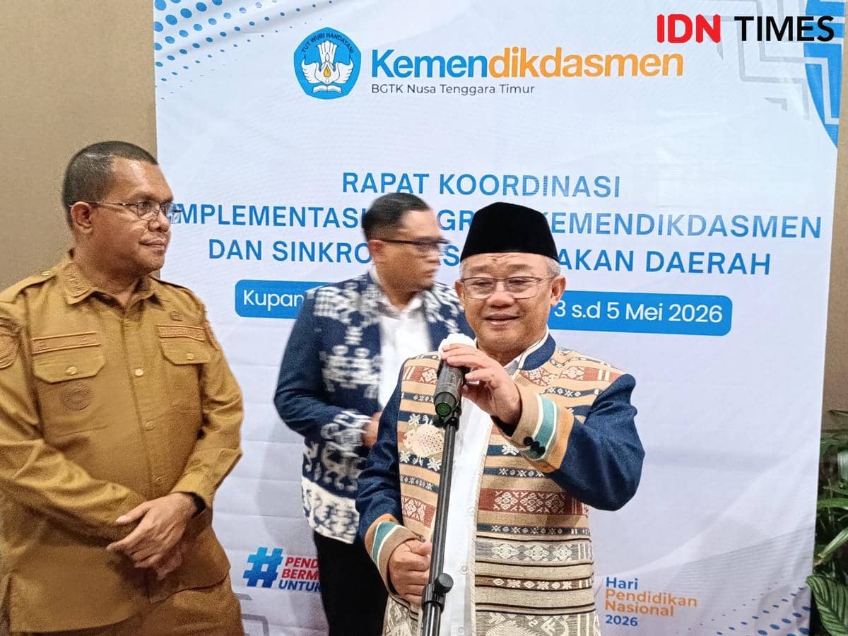 Seorang pejabat berbicara di depan mikrofon saat rapat koordinasi Kemdikdasmen di Kupang, didampingi dua pria lainnya.
