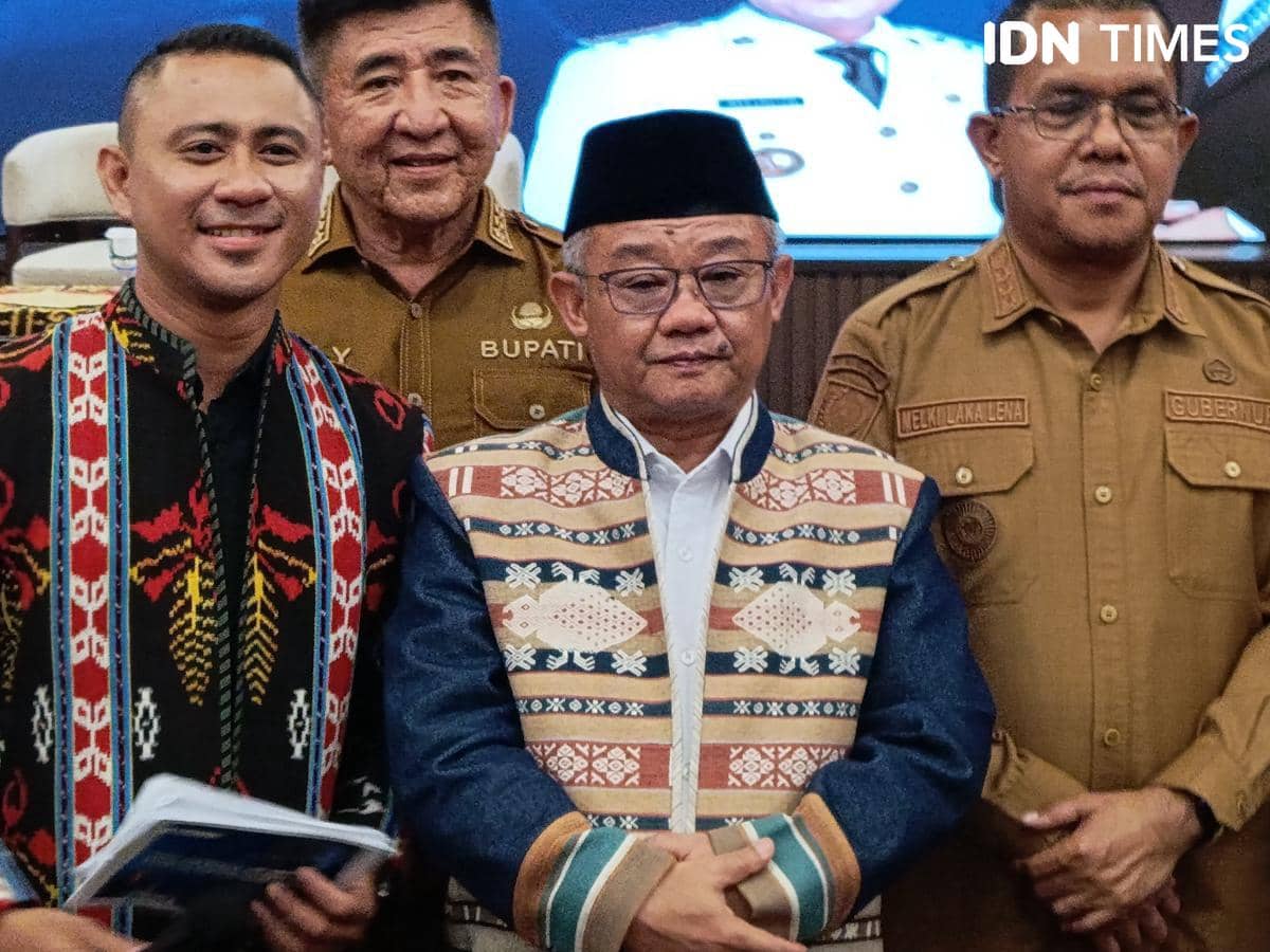 Seorang pejabat mengenakan pakaian adat berdiri di tengah bersama tiga pria lainnya dalam acara kunjungan di Kupang.