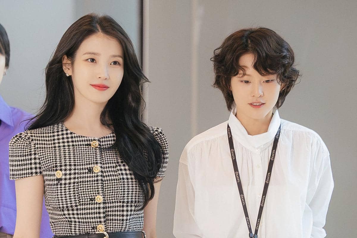 Dua pemeran utama drama Korea Perfect Crown berdiri berdampingan, satu mengenakan gaun bermotif kotak dan satu mengenakan kemeja putih.