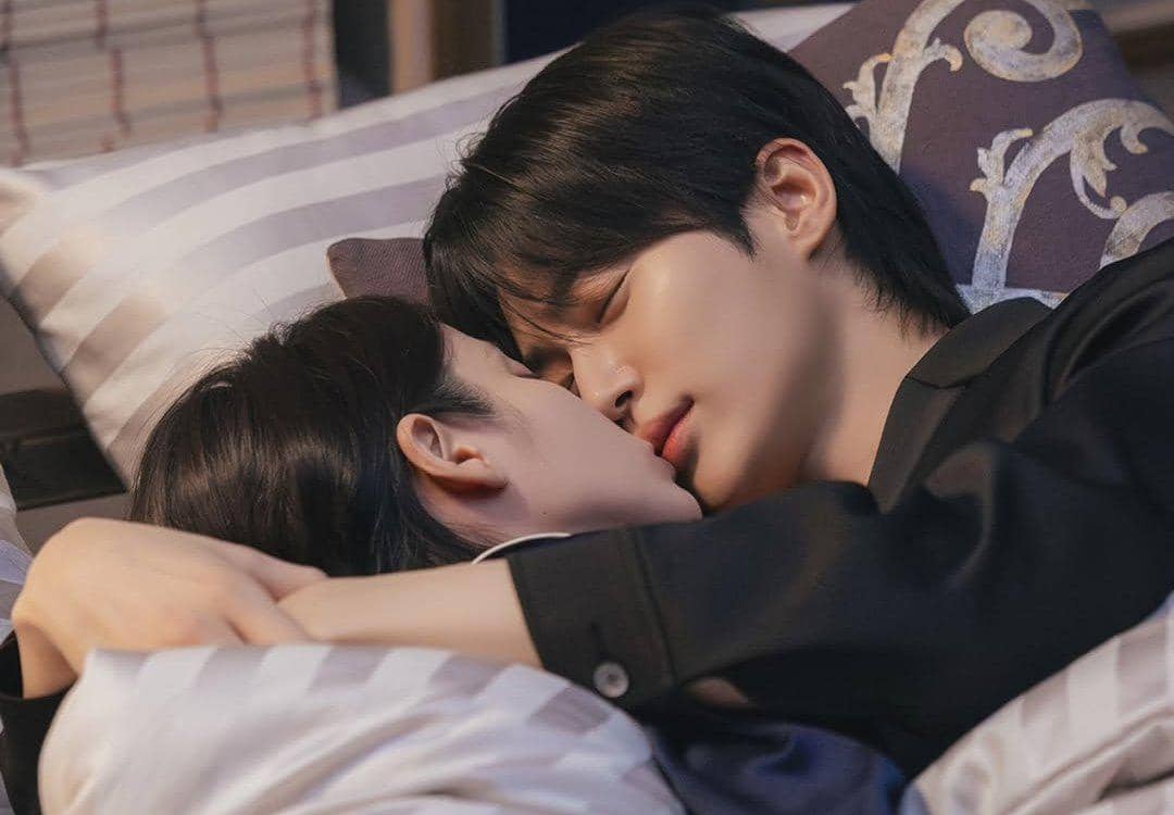 Dua karakter dalam drama Korea Perfect Crown berbaring di tempat tidur sambil berpelukan dan saling menatap dengan lembut.