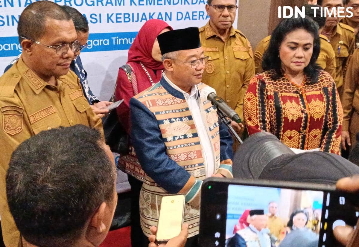 Seorang pejabat mengenakan pakaian adat berbicara di depan mikrofon didampingi beberapa orang dalam acara kunjungan di Kupang.