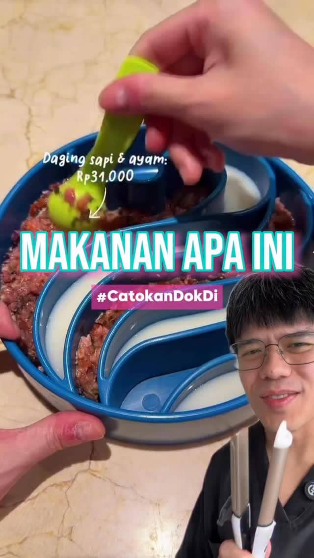 Seseorang memegang sendok hijau dan menyiapkan campuran daging sapi dan ayam di wadah biru bertuliskan harga Rp31.000 dengan teks Makanan Apa Ini.