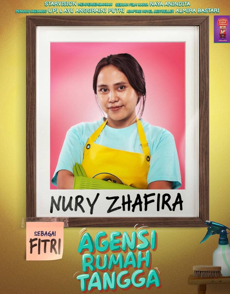 Nury Zhafira mengenakan celemek kuning dan kaus biru muda berpose di depan latar merah muda sebagai karakter Fitri dalam film Agensi Rumah Tangga.