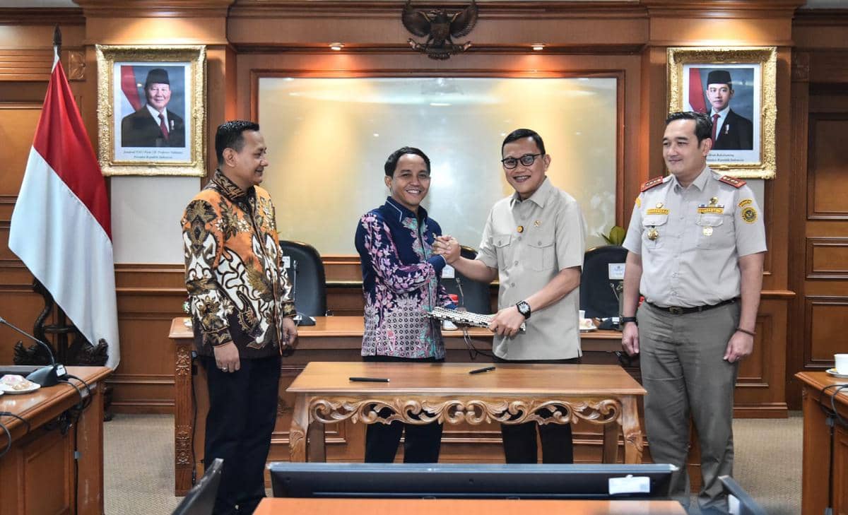 Pejabat Kementerian Kehutanan dan Badan Karantina Indonesia berjabat tangan usai penandatanganan nota kesepahaman di ruang pertemuan resmi.