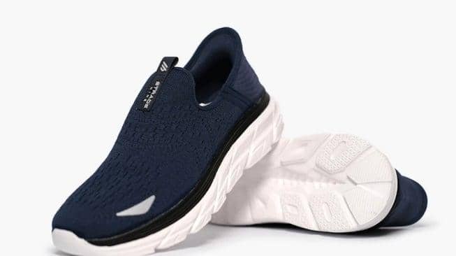 Sepasang sepatu slip-on berwarna biru tua dengan sol putih tebal dan desain rajutan modern, tampak dari sisi depan dan bawah.