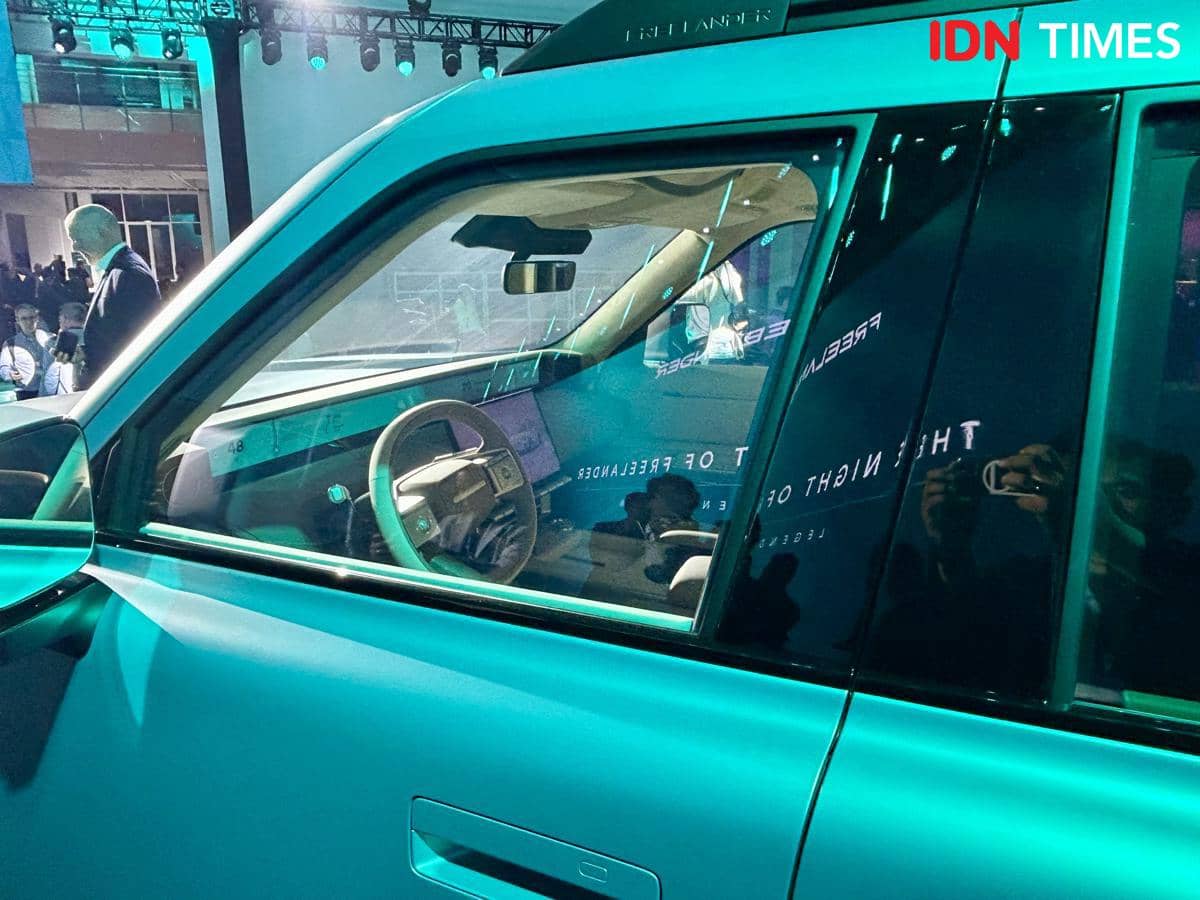 Tampilan interior mobil Freelander 8 terlihat melalui jendela samping dengan setir dan dasbor modern di bawah pencahayaan biru.