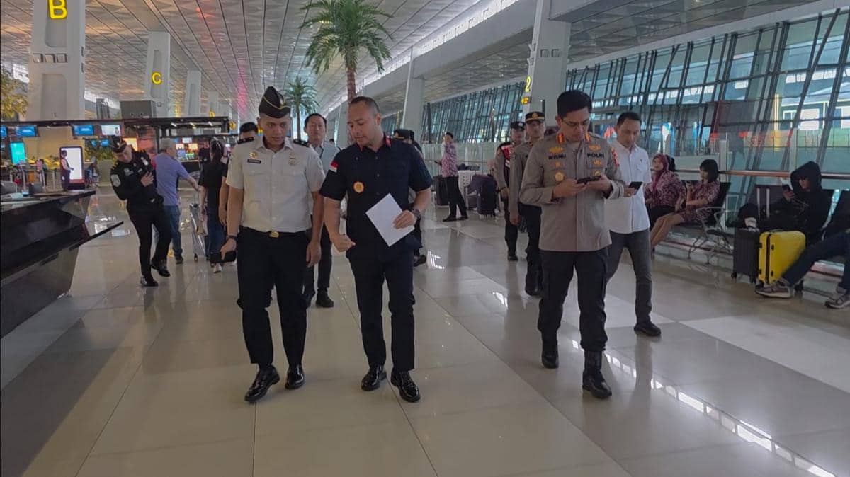 Petugas Polres dan Imigrasi Bandara Soekarno-Hatta berjalan bersama di area terminal bandara saat melakukan patroli pengamanan.