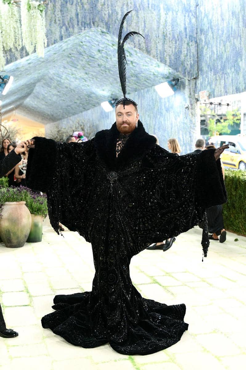 Seorang tamu mengenakan jubah hitam berkilau dengan bulu tinggi di kepala saat menghadiri Met Gala 2026 di New York.