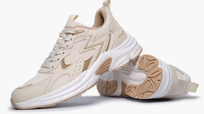 Sepasang sepatu sneakers warna krem dengan sol tebal putih dan detail cokelat muda, bergaya kasual dan sporty.