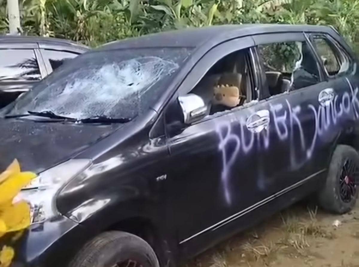Mobil berwarna hitam milik wisatawan asal Surabaya mengalami kerusakan parah dengan kaca depan pecah dan coretan cat di bagian pintu.