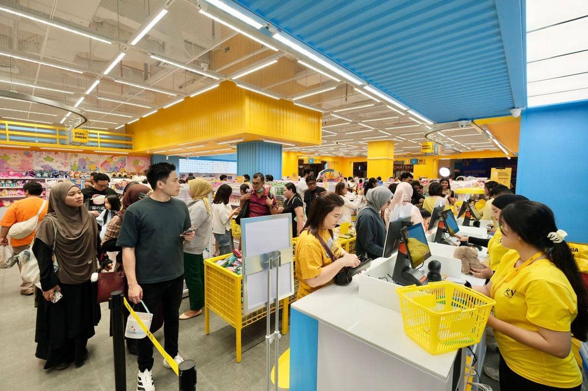 Suasana ramai di dalam toko KKV dengan pelanggan mengantre di kasir dan karyawan mengenakan seragam kuning melayani pembeli.