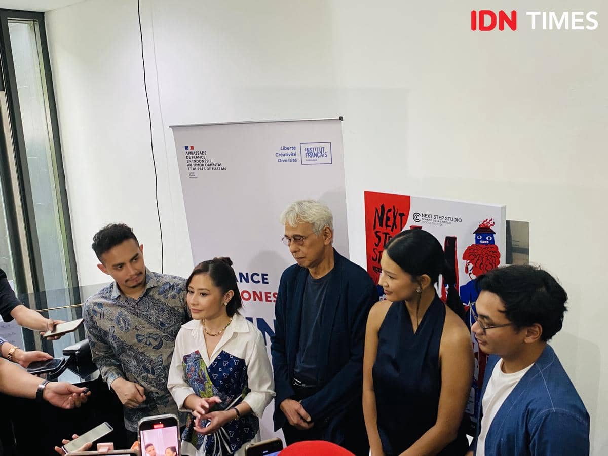 Beberapa orang berdiri bersama saat konferensi pers Next Step Studio Indonesia dengan latar belakang banner acara dan media yang meliput.