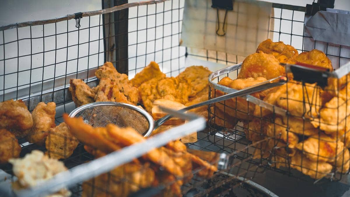 Beragam gorengan seperti tempe, tahu, dan pisang goreng ditiriskan dalam keranjang kawat setelah digoreng hingga keemasan.