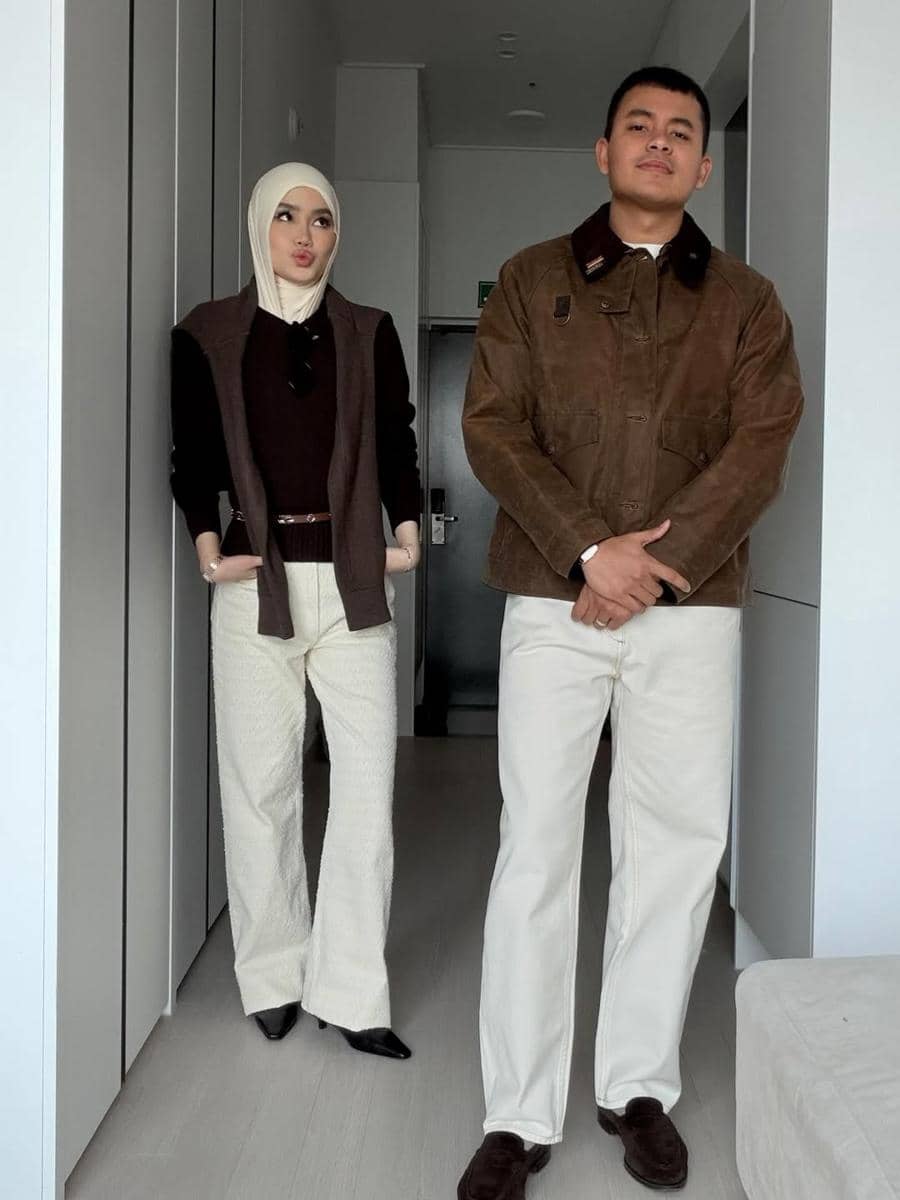 Sepasang pria dan wanita berpose di dalam ruangan dengan busana bernuansa cokelat dan krem, menampilkan gaya OOTD couple yang serasi.