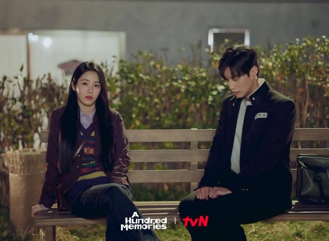 Dua karakter duduk di bangku taman pada malam hari dalam adegan drama A Hundred Memories yang tayang di tvN.
