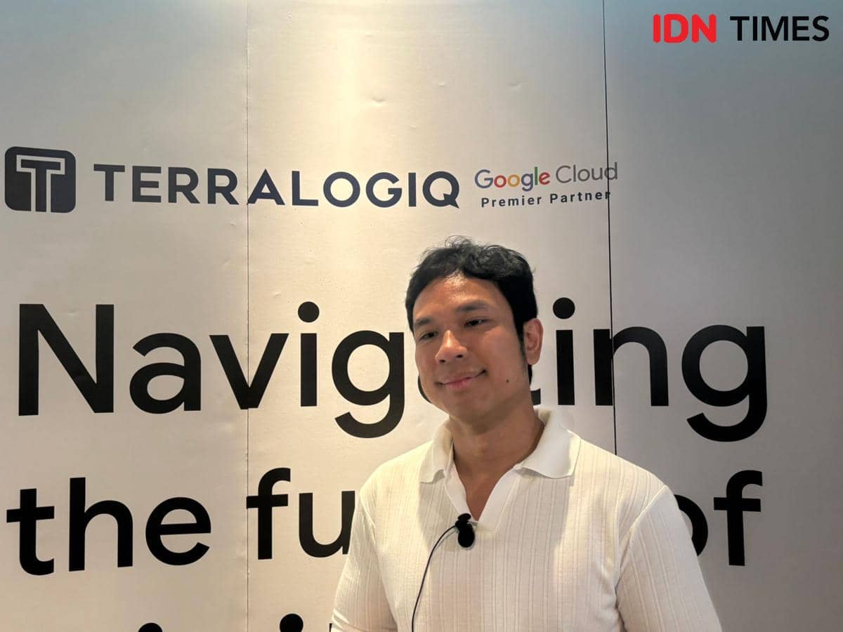Seorang pria mengenakan kemeja putih berdiri di depan latar bertuliskan Terralogiq dan Google Cloud Premier Partner dalam sebuah acara.