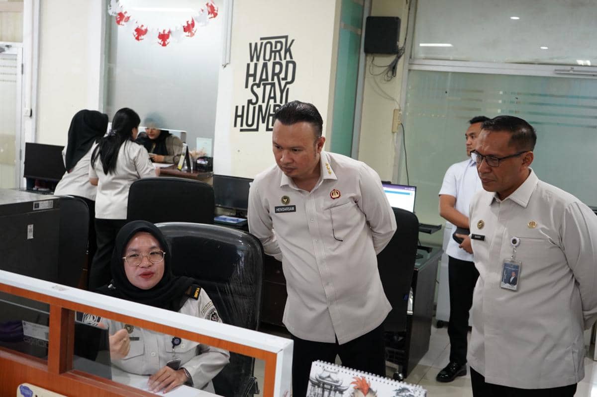 Pejabat imigrasi mengenakan seragam putih memantau aktivitas petugas di kantor Imigrasi Tangerang dengan suasana kerja aktif.