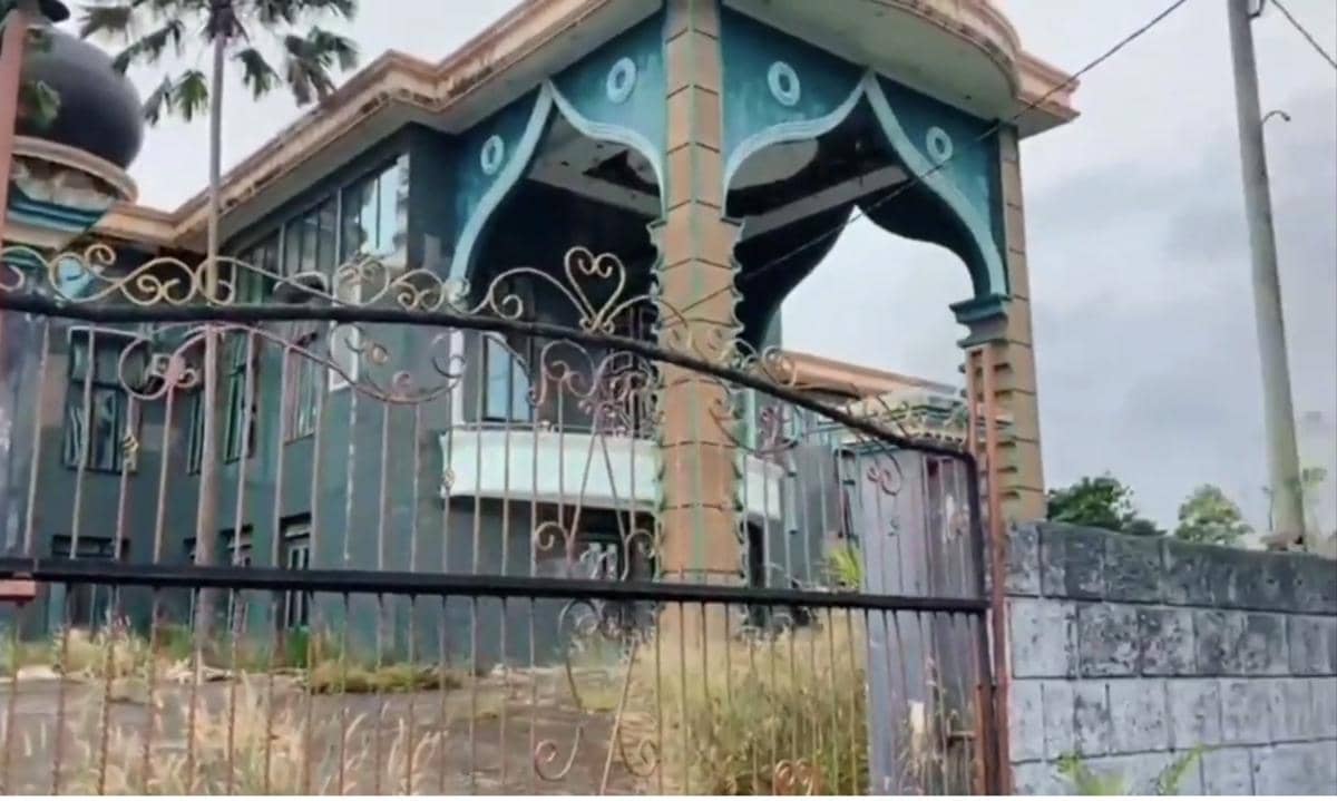 Bangunan besar bergaya istana dengan gerbang besi dan arsitektur unik berwarna biru kehijauan di Istana Tunggang Bosar.