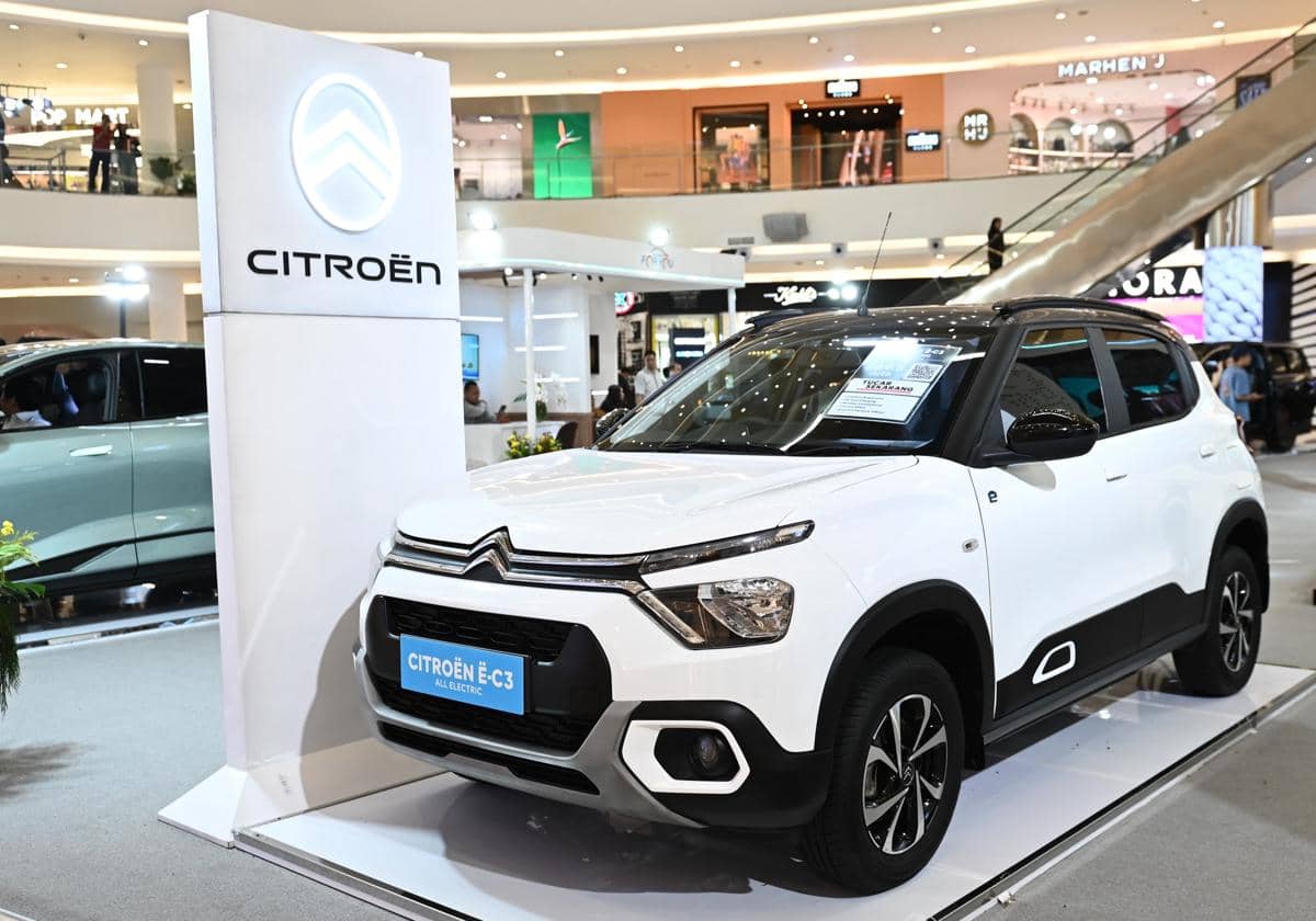 Mobil listrik Citroën ë-C3 berwarna putih dipamerkan di area pameran dalam pusat perbelanjaan dengan pencahayaan modern.