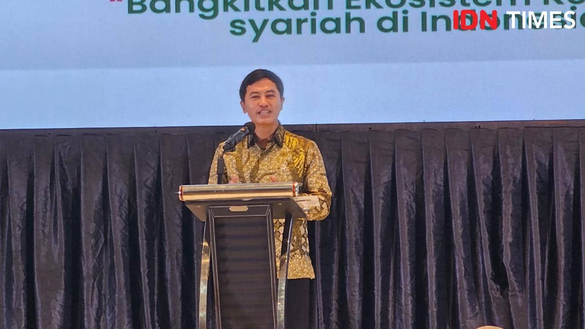 Seorang pria mengenakan batik berdiri di podium dengan mikrofon, berbicara di acara bertema ekonomi syariah di Tangerang.