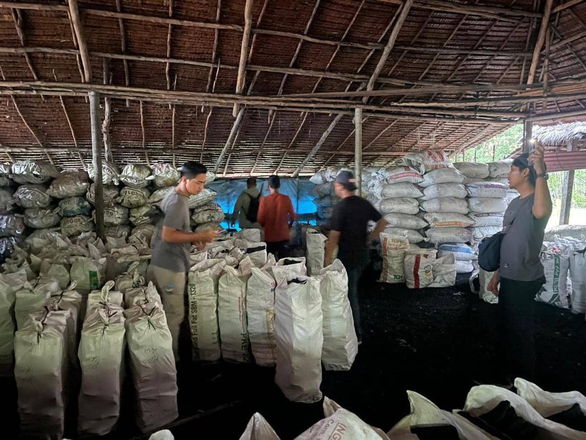 Petugas berada di dalam gudang berisi tumpukan karung berwarna putih yang diduga berisi hasil pembakaran kayu mangrove di Kepulauan Meranti.
