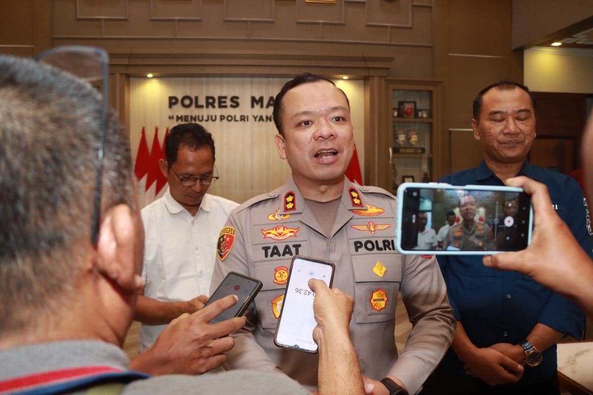 Seorang perwira polisi berseragam sedang memberikan keterangan kepada wartawan di kantor Polres Malang dengan beberapa orang di sekitarnya.