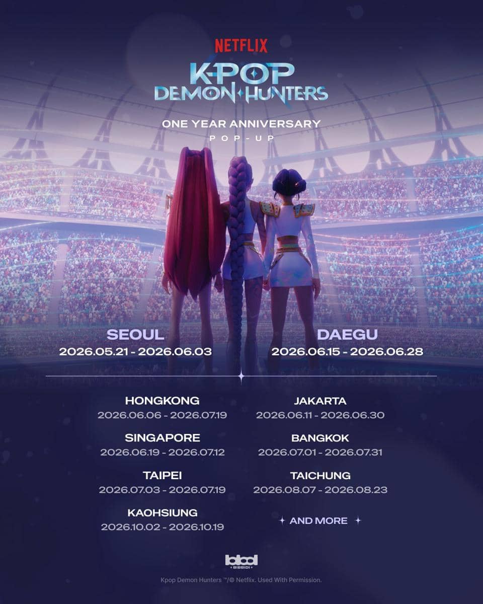 Tiga karakter animasi KPop Demon Hunters berdiri di panggung besar dengan latar penonton, menandai acara pop-up ulang tahun pertama Netflix.
