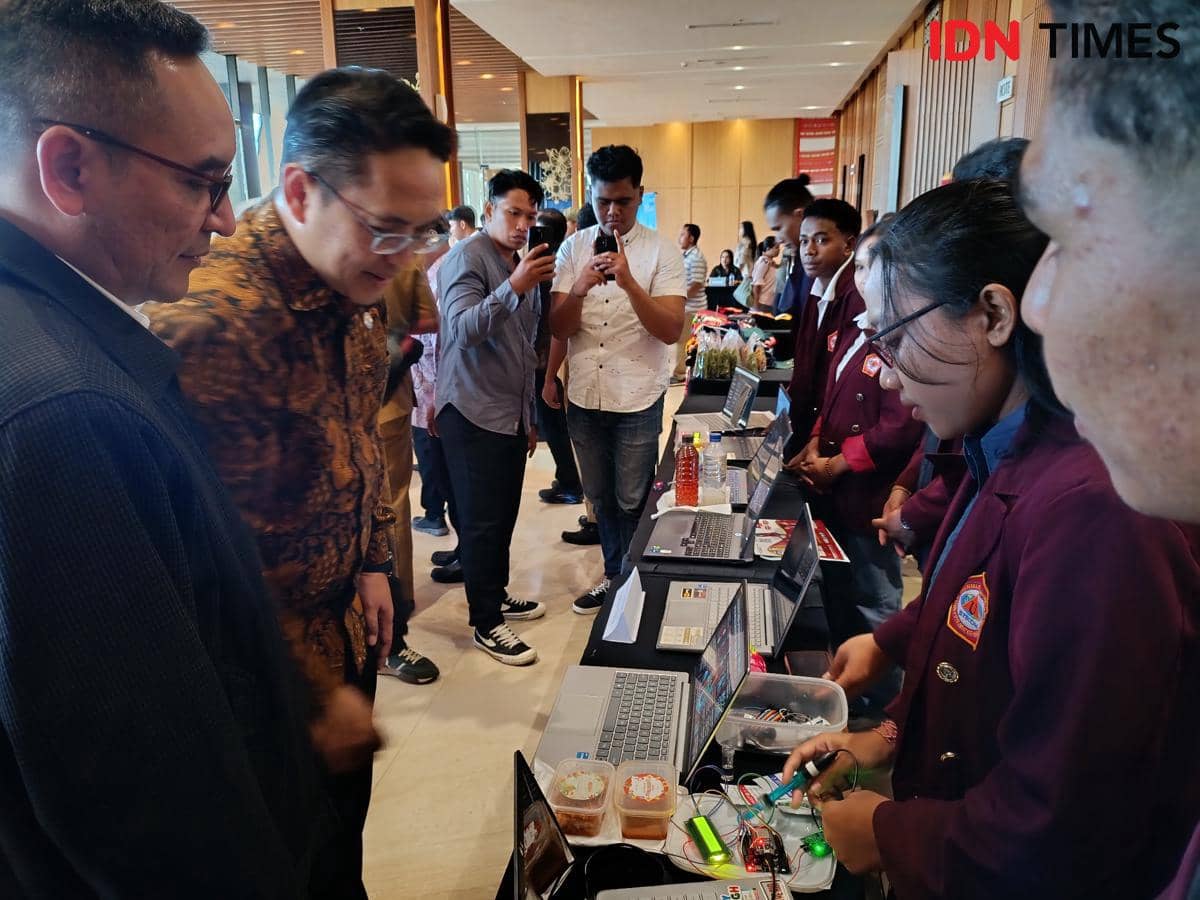 Seorang pejabat melihat hasil karya mahasiswa yang dipamerkan di atas meja dengan laptop dan perangkat elektronik di Kota Kupang.