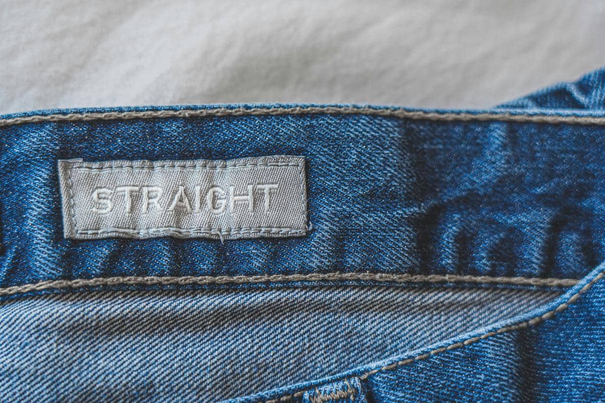 Label bertuliskan 'STRAIGHT' pada bagian dalam celana jeans biru model straight leg dengan detail jahitan denim.