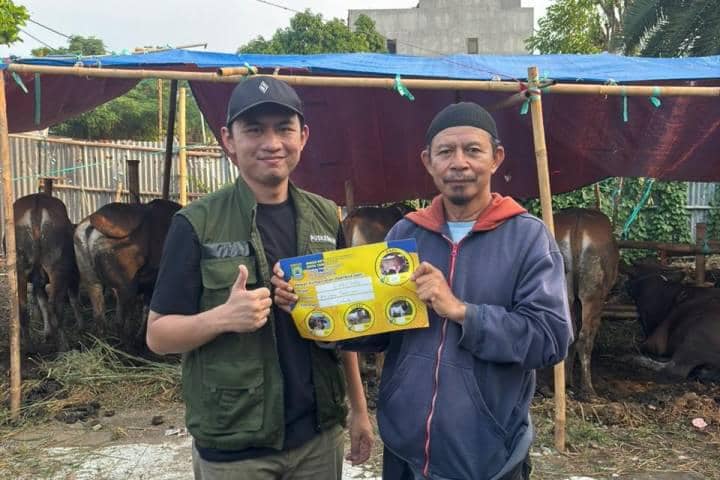 Petugas DKP Kota Tangerang bersama pedagang hewan kurban memegang brosur pemeriksaan kesehatan di lapak sapi kurban.