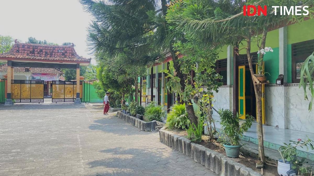 Halaman SDN Kowang Jetis di Kabupaten Bantul dengan gerbang utama bercat kuning dan bangunan sekolah berwarna hijau dikelilingi pepohonan.