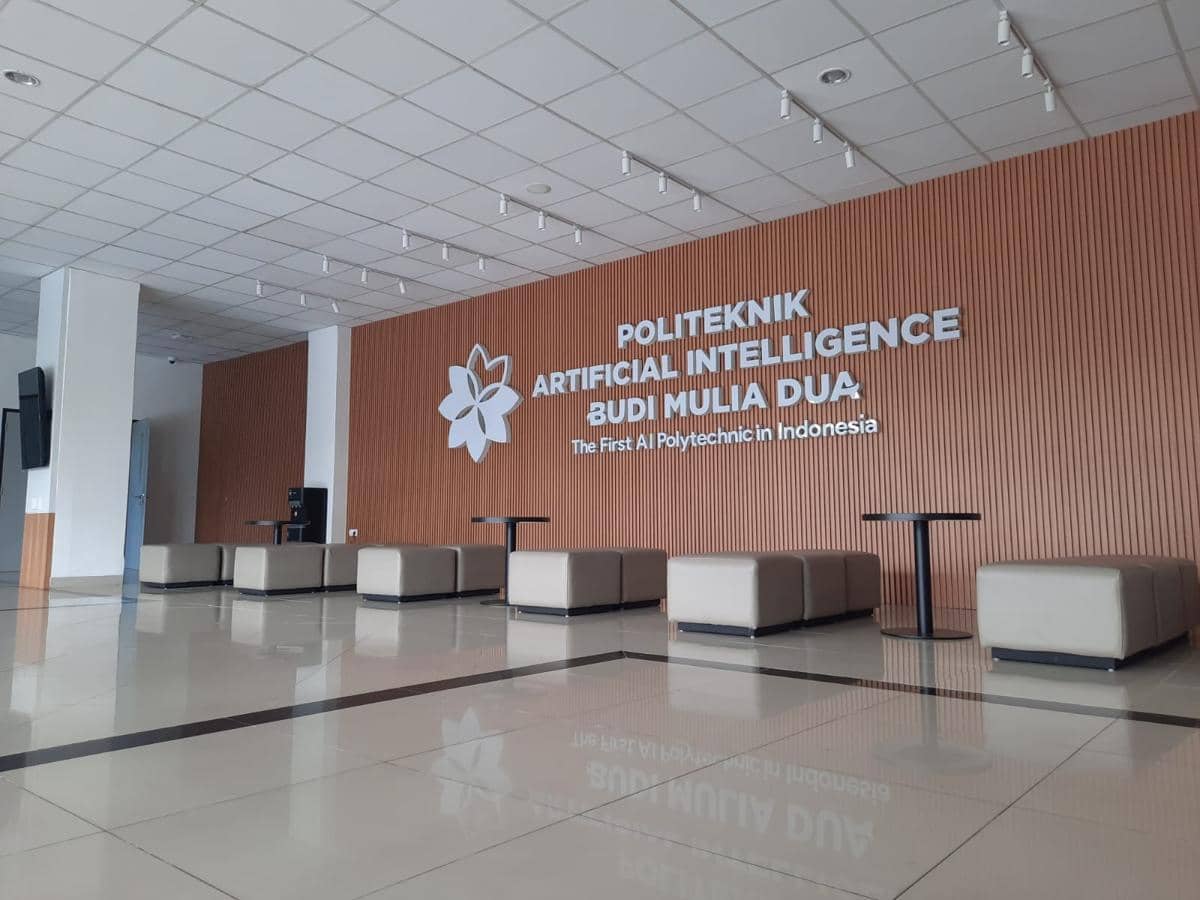 Lobi kampus Politeknik Artificial Intelligence Budi Mulia Dua dengan dinding kayu berlogo institusi dan deretan kursi modern.