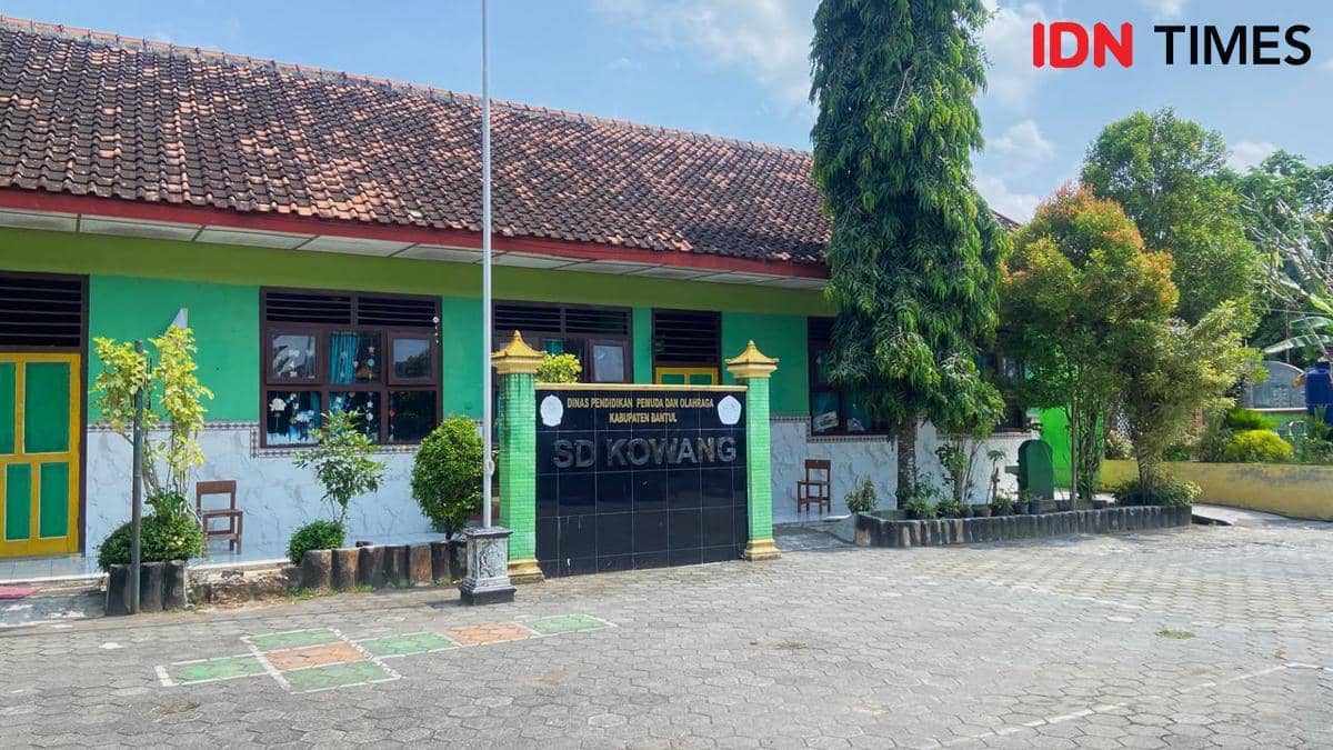 Bangunan SDN Kowang Jetis di Kabupaten Bantul dengan dinding hijau, halaman luas, serta pepohonan rindang di sekitarnya.