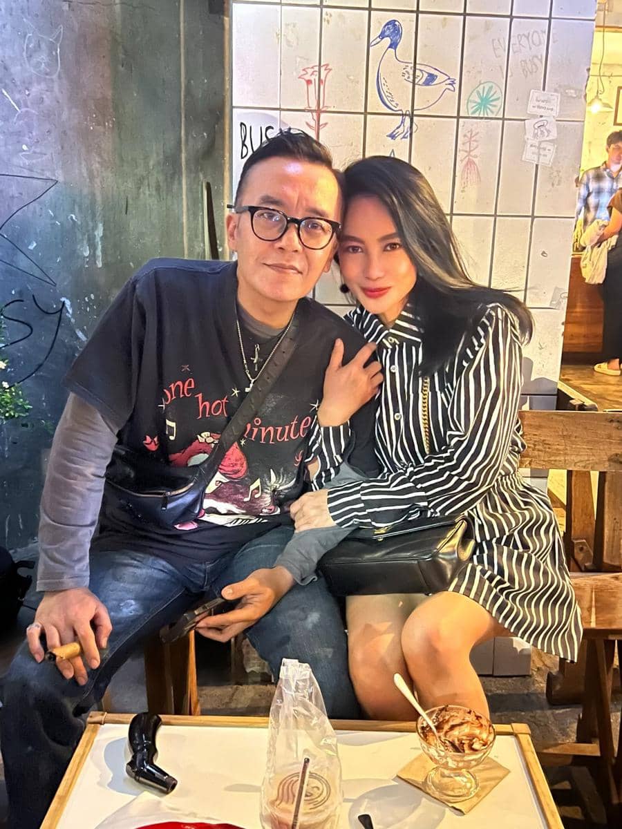 Seorang pria dan wanita duduk berdekatan di kafe dengan suasana hangat, menikmati waktu bersama di meja dengan es krim dan minuman.