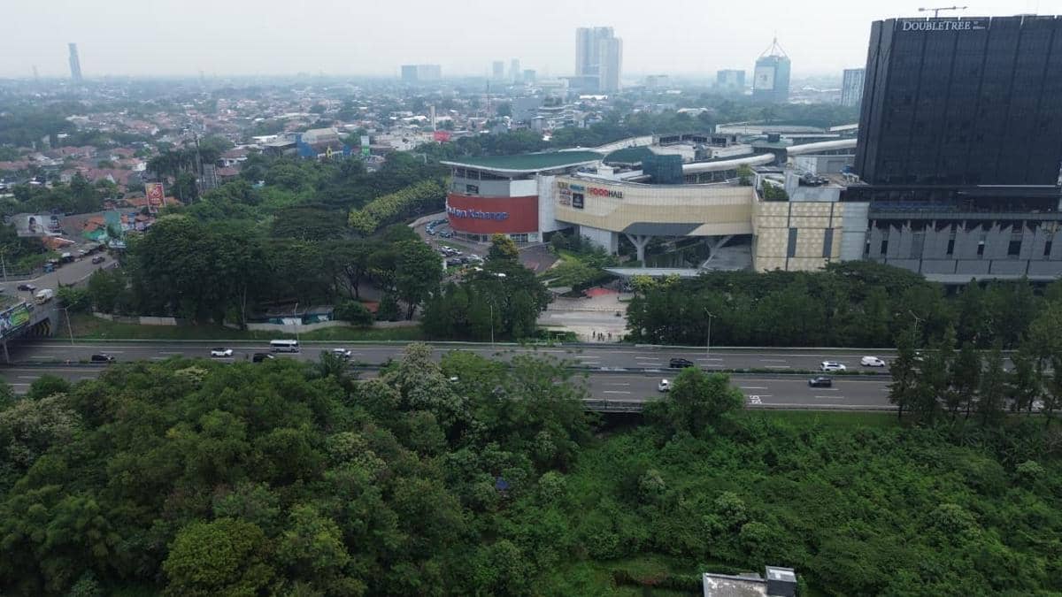Pemandangan udara Bintaro XChange Mall dengan area hijau di sekitarnya dan jalan tol yang ramai di depan pusat perbelanjaan.