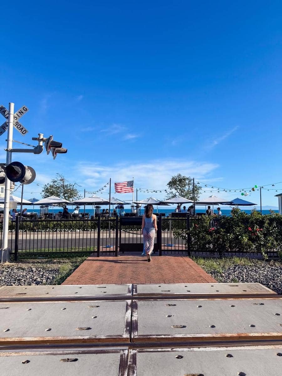 Seorang wanita berjalan menuju area dengan bendera Amerika Serikat di bawah langit biru cerah di California.