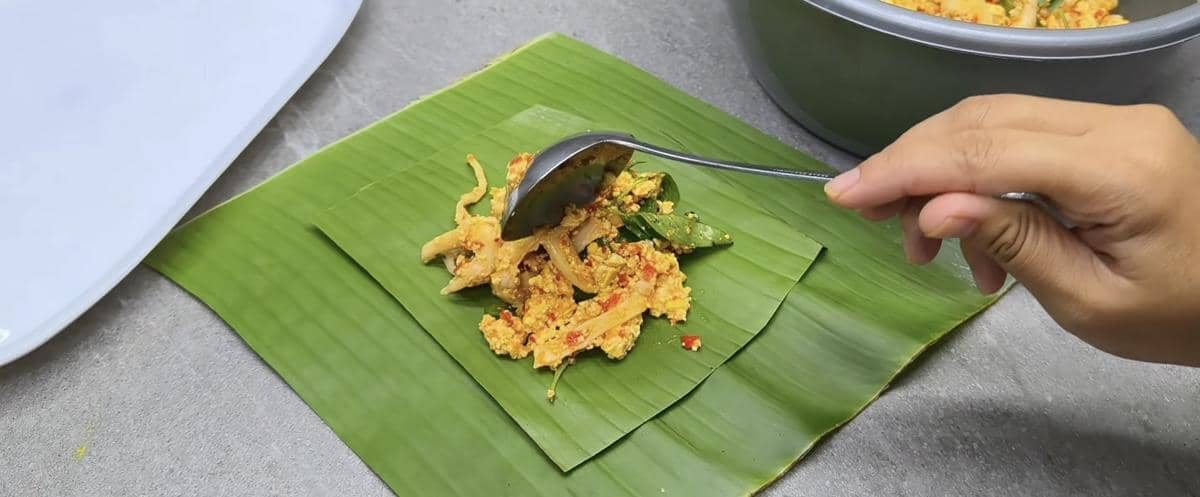 ilustrasi mengisikan pepes tahu jamur di atas daun pisang