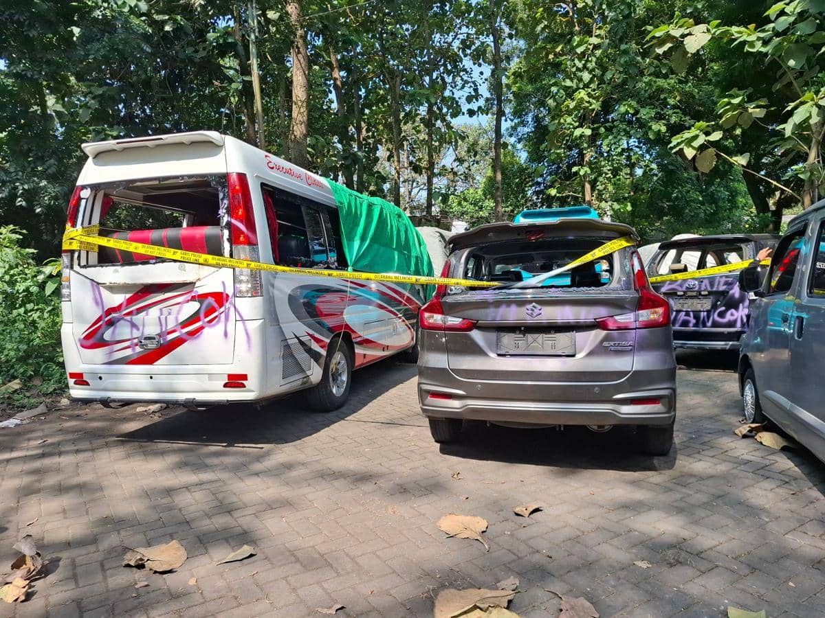 Beberapa kendaraan wisatawan asal Surabaya yang dirusak di Pantai Wedi Awu, dengan kaca pecah dan garis polisi mengelilinginya.