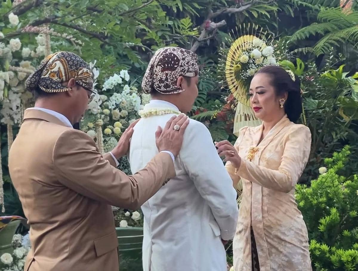 Prosesi akad nikah adat Jawa di luar ruangan dengan pasangan mengenakan busana tradisional dan ornamen bunga di latar belakang.