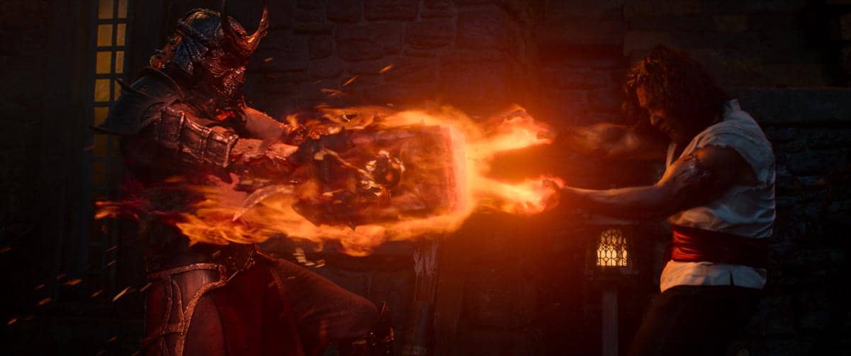 Dua karakter bertarung sengit di adegan film Mortal Kombat 2, saling menyerang dengan energi api menyala di antara mereka.