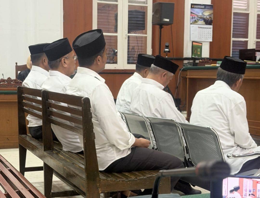 Enam pria mengenakan kemeja putih dan peci hitam duduk di ruang sidang Pengadilan Negeri Makassar saat pembacaan vonis.
