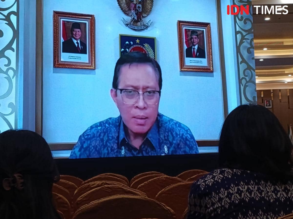 Seorang pejabat pemerintah tampil secara virtual di layar besar saat Musrembang Provinsi Nusa Tenggara Timur dengan peserta menyimak di ruangan.