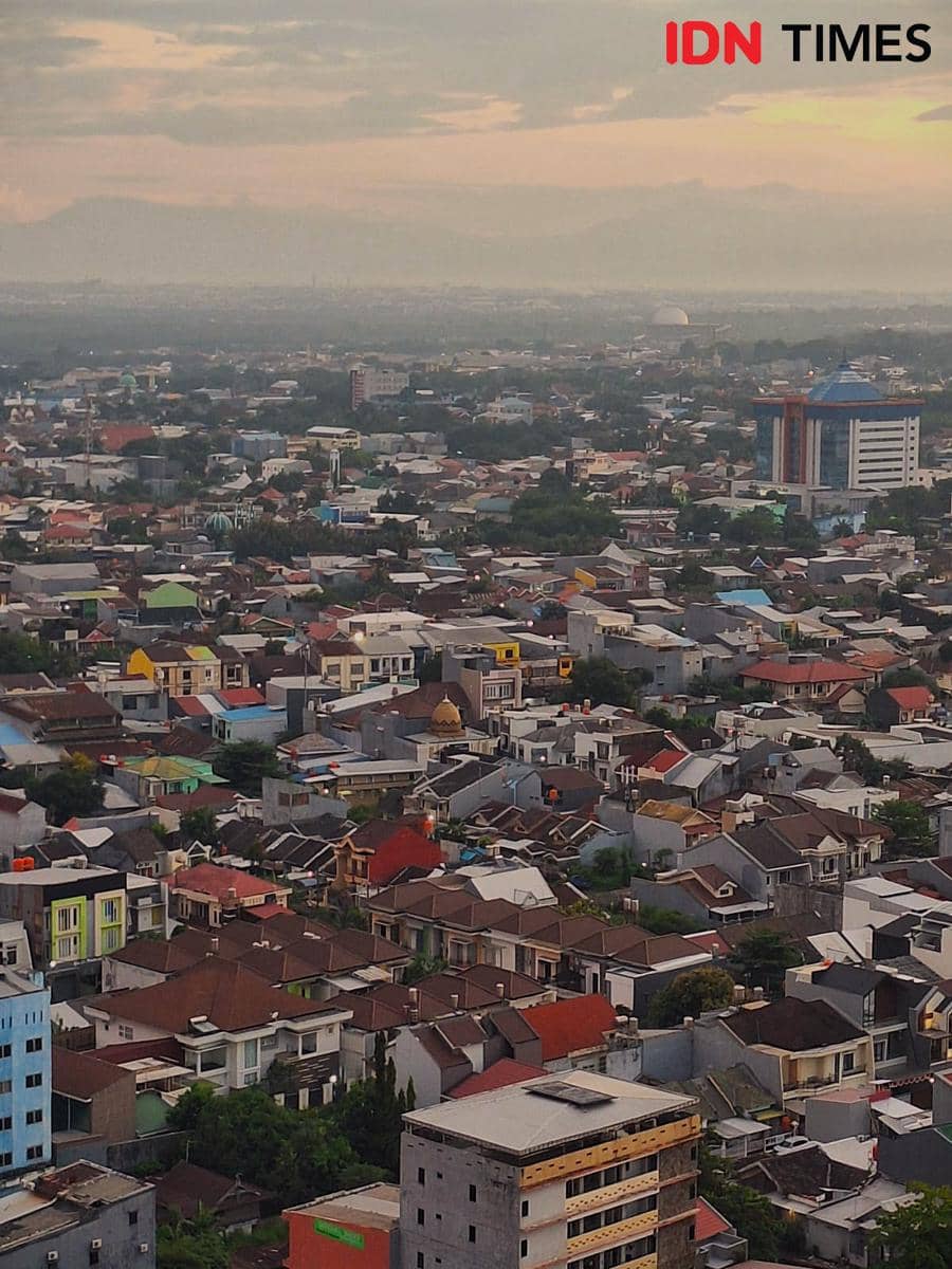 Pemandangan udara Kota Makassar pada Oktober 2025 dengan deretan bangunan dan rumah padat di bawah langit senja yang berawan.
