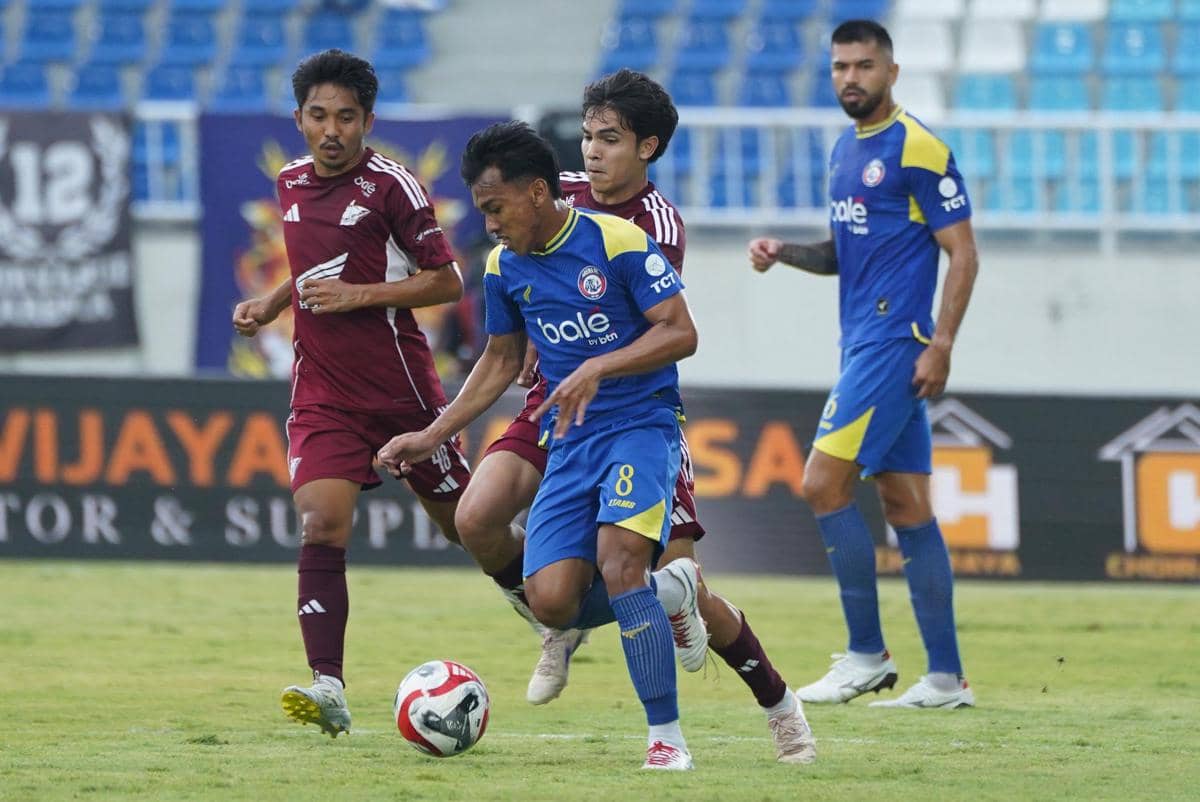 Pemain Arema FC dan PSM Makassar berebut bola dalam pertandingan Liga 1 di Stadion Kanjuruhan dengan latar tribun penonton kosong.
